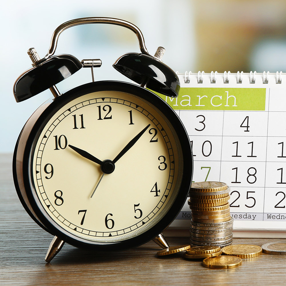 photo of an alarm clock, coins, and a calendar on a table