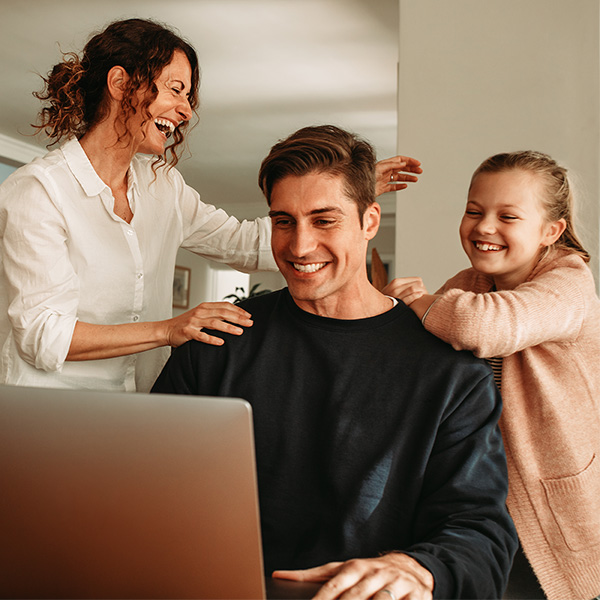 photo of a family laughing together while using a laptop